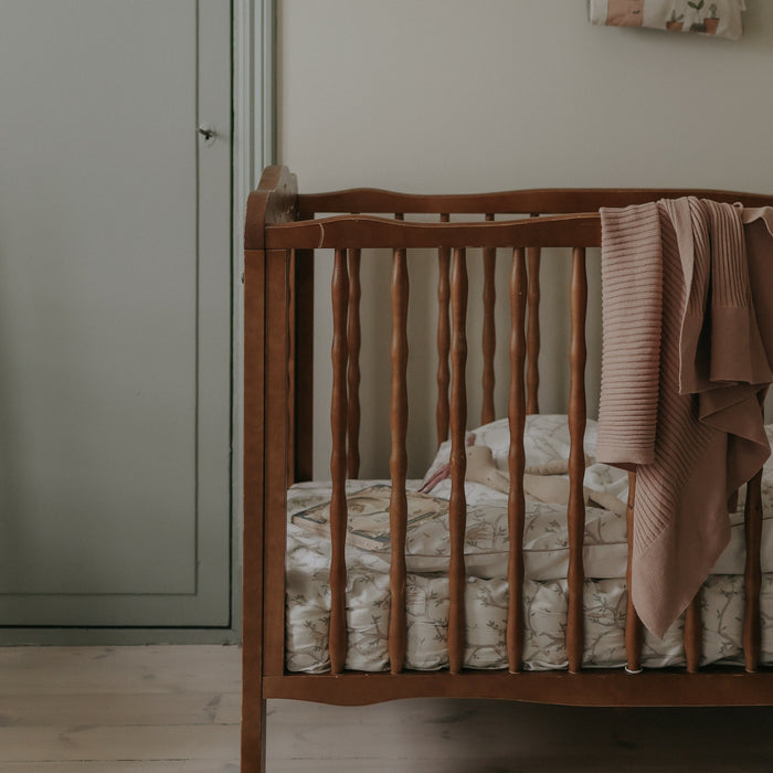 Animal Parade Baby Duvet in Ivory. Crib in room with duvet inside and blanket hanging over crib.