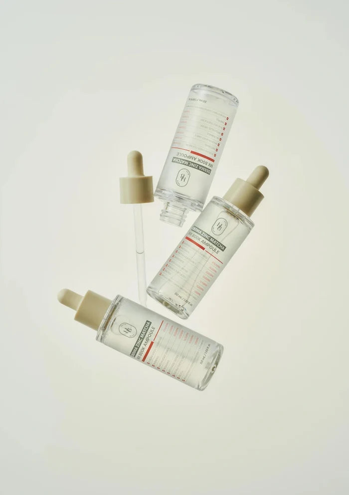 Four skincare bottles with droppers on a light background
