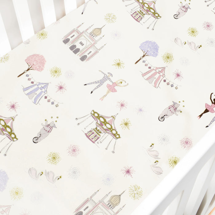 Crib sheet with vintage carnival design featuring castles, fireworks, and dancers on a white background.