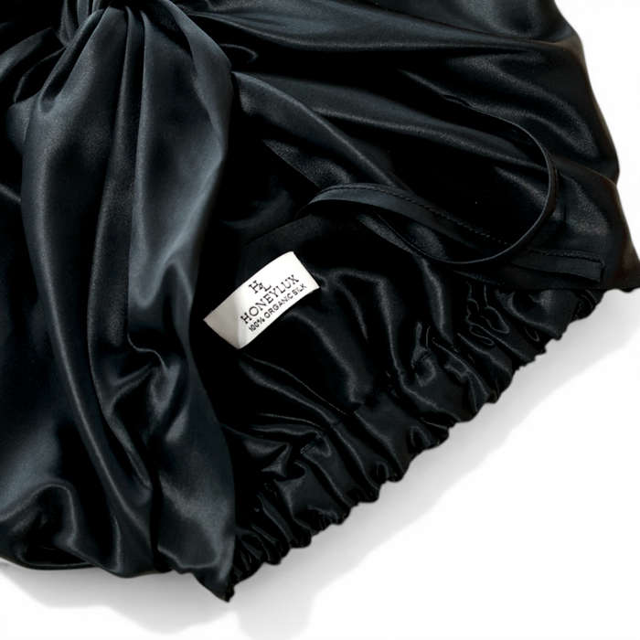 Black silk hair bonnet with 'HONEYLUX' 100% Oraganic Silk label on a light background