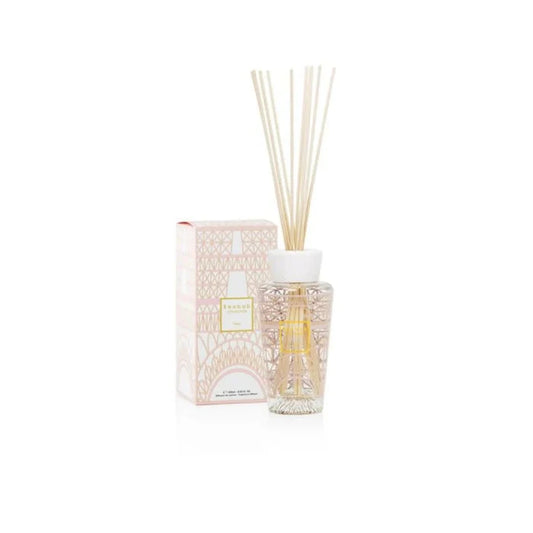 A home fragrance diffuser with a pink and gold silk-screen print, depicting a stylized Eiffel Tower structure, accompanied by a box with a similar design.