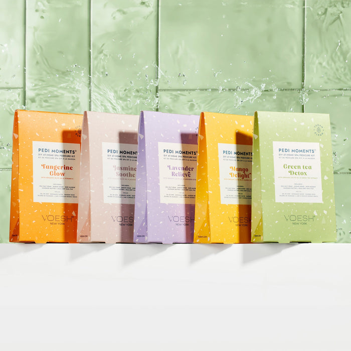 Five Voesh pedicure bags with different scents on a light green textured background